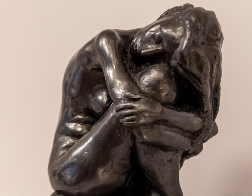 Skulptur av kvinne som klemmer kneet sitt